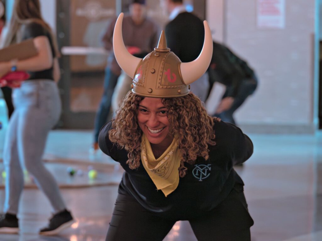 Women bending forward while wearing viking helmet and smiling